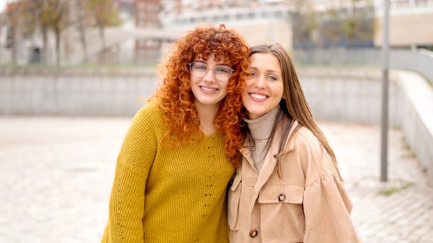 Two young women standing smiling together in the street