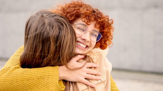 Two women embracing during a happy meeting between two young friends in the street. Close up