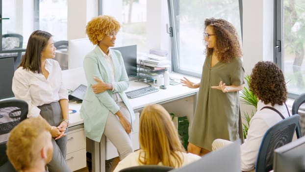 Happy manager giving good news to employees during a meeting in a coworking