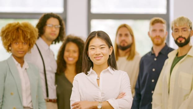 Chinese woman leading a work team in the office standing proud and looking at camera together