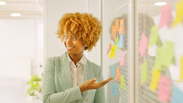 African woman pointing a post-it to present ideas in a meeting