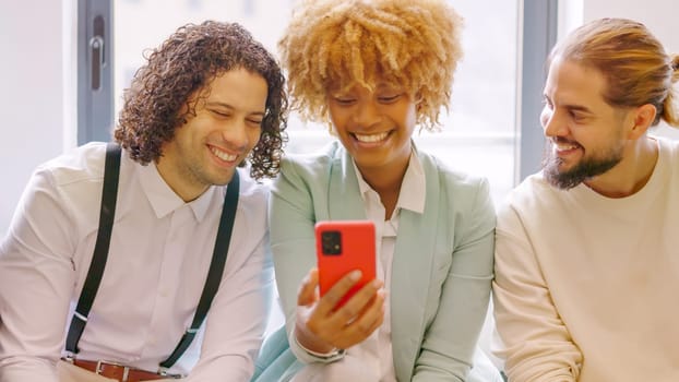 Multi-ethnic coworkers using phone sitting relaxed during a break