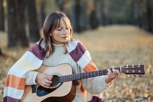 Musician guitarist girl practicing in autumn forest