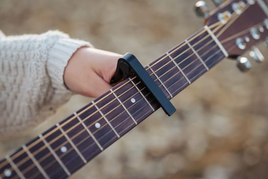 Play the guitar using a capo (musical device)