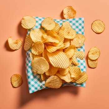 Crunchy potato chips on a checkered napkin, top view
