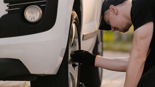 Mechanic Repairs Car, Working Diligently To Unscrew Wheel Bolt