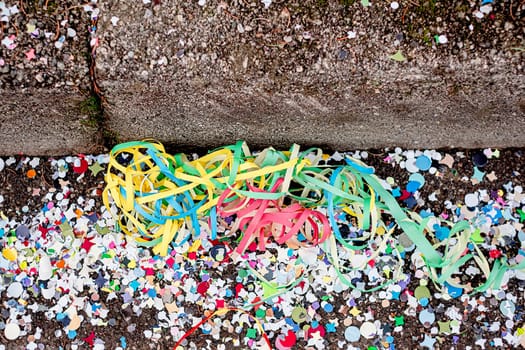 Close up colorful confetti and streamers at the street after Carnival parade