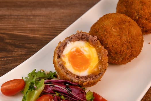 RECIPE FOR BREADED BEEF MEATBALLS STUFFED WITH A SOFT BOILED EGG. High quality photo