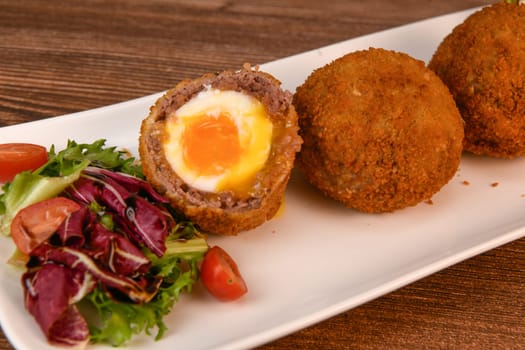 RECIPE FOR BREADED BEEF MEATBALLS STUFFED WITH A SOFT BOILED EGG. High quality photo