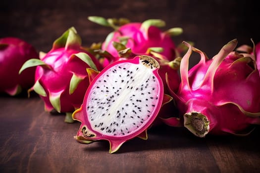 Vibrant dragon fruit sliced open to reveal black-seeded white flesh on a wooden surface.