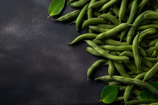 Fresh green beans arranged on a dark surface with leaves.