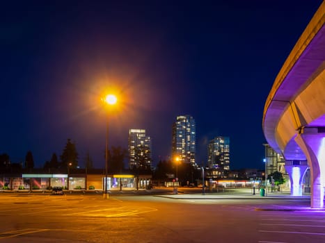 Night cityscape with skytrain line and bright street light over the plaza