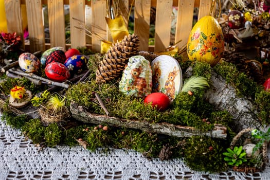On a bed of lush moss, twigs and birch bark intertwine with vibrant greenery, forming a rustic backdrop for colorful Easter eggs. Among them, one bears the joyful inscription of , Alleluia, adding a touch of celebration to the tableau.