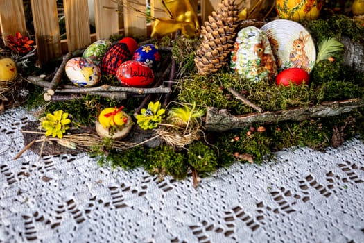On a bed of lush moss, twigs and birch bark intertwine with vibrant greenery, forming a rustic backdrop for colorful Easter eggs. Among them, one bears the joyful inscription of , Alleluia, adding a touch of celebration to the tableau.