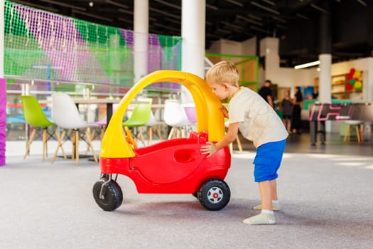 Young boy pushing a toy car in a vibrant indoor play area