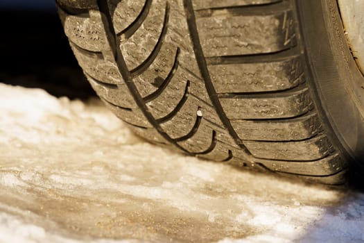 Winter tire. Close-up of the tread of a winter car tire on the road in winter.