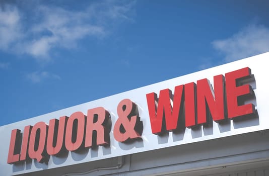 A Sign For A Liquor And Wine Store Against A Bright Blue Sky