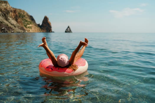 Summer vacation woman in hat floats on an inflatable donut mattress. Happy woman relaxing and enjoying family summer travel holidays travel on the sea