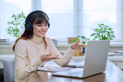 Teenage girl college student in headphones having video conference chat online meeting lesson webinar on computer laptop screen, sitting at desk at home. E-learning, education, technology, knowledge