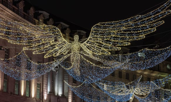 London, UK - Dec 25, 2023 - Flying angel Christmas decoration led lights display. Dramatic view of the traditional Christmas decoration lights hanging above Regent Street during dusk, The Spirit of Christmas, Light Festival in London, Space for text, Selective focus.