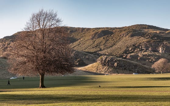 The breathtaking scenic landscape of Holyrood park with Salisbury Crags rugged hills and sky background. View of Edinburgh city. Space for text, Selective focus.
