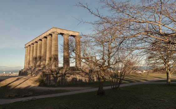Edinburgh, Scotland - Jan 18, 2024 - A view of the National Monument of Scotland with a bright blue sky in the background situated on Calton Hill at Edinburgh city. Scotland, Space for text, Selective focus.