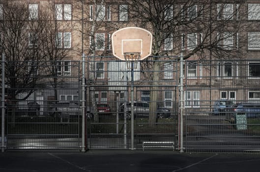 Edinburgh, Scotland, Jan 19, 2024 - Basketball backboard with the hoop metal ring at outdoor basketball courts in the park with old buildings background in the city downtown. Space for text, Selective focus.