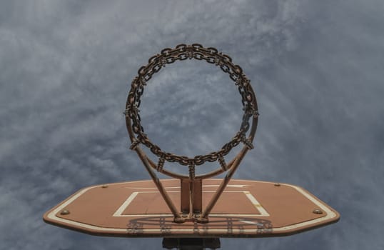 Edinburgh, Scotland, Jan 19, 2024 - View of Basketball backboard with the hoop metal ring and steel chain net against blue sky background seen from below. Street basketball court, Low angle view, Look up, Space for text, Selective focus.