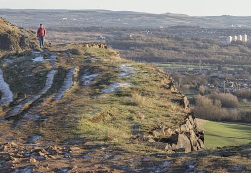 Edinburgh, Scotland - Jan 17, 2024 - A Man hiking walking through Mountain ridge on the Salisbury Crags. Destinations in Europe, Space for text, Selective focus.