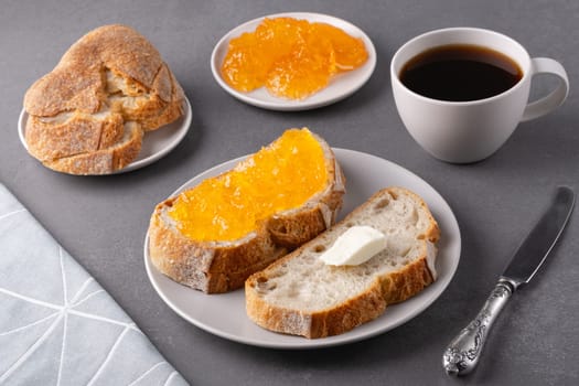 Sandwiches with apricot jam and a cup of coffee on a gray background. Breakfast concept.