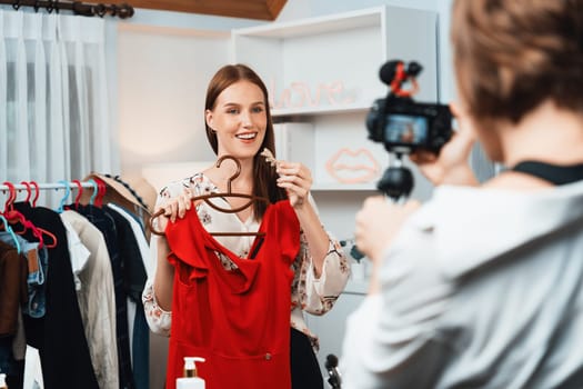 Woman influencer shoot live streaming vlog video review clothes utmost social media or blog. Happy young girl with apparel studio lighting for marketing recording session broadcasting online.