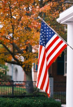 A USA Flag On A Porch In Vermont Against Beautiful Fall Colors