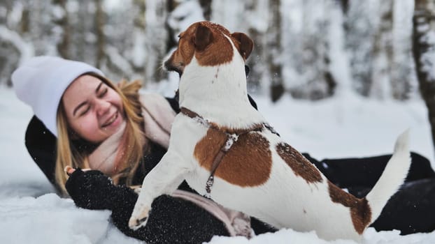 A girl playing with her Jack Russell Terrier dog in the snow