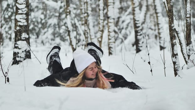 A girl falls on the snow in winter in the forest