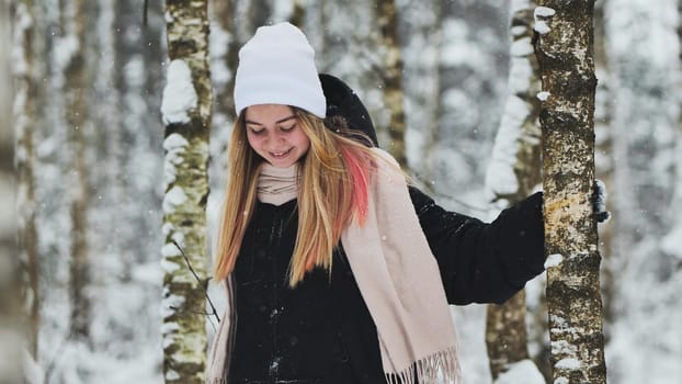 A girl walking in the forest in winter among the birches