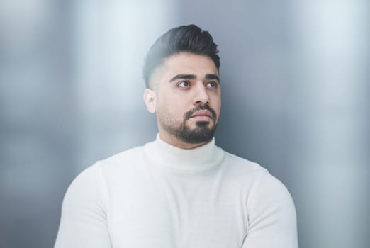 Portrait of a stylish man posing on a gray background with his arms crossed