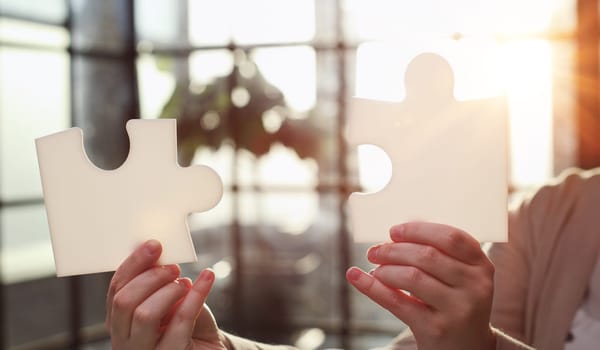 Business Woman holding two blank white puzzle pieces in his hands conceptual of solving a problem