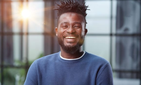 Handsome charming cheerful african american businessman in chic colorful casual clothes, in an office building