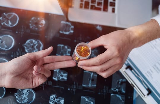 Close-up of hands of a doctor giving medicine to a patient on the background of an x-ray