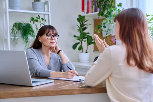 Middle-aged female psychologist, psychotherapist, counselor, social worker working with young woman patient. Psychology therapy professional help consultation treatment support mental health concept