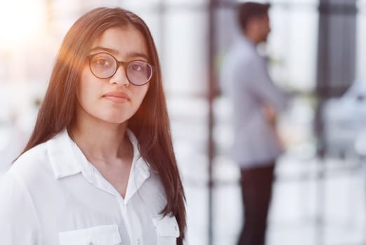 a girl stands in a modern office and looks at the camera