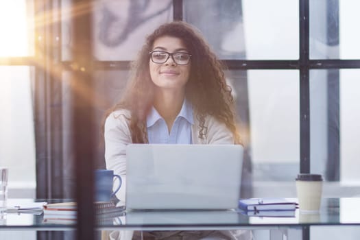Young businesswoman using laptop at table in office