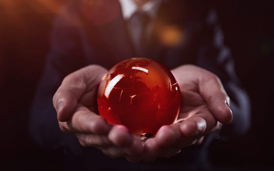 businessman holds glass globe with continents in hands