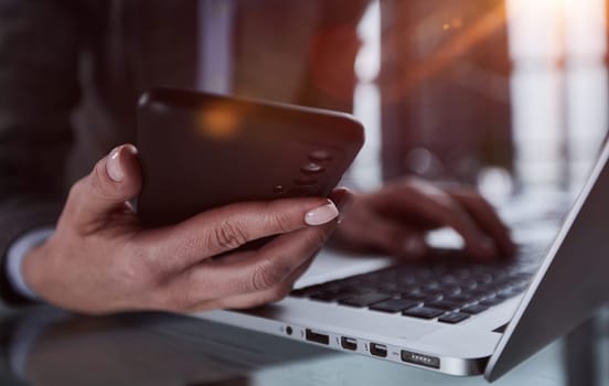 male hands hold a smartphone and use it for online shopping while looking at a laptop