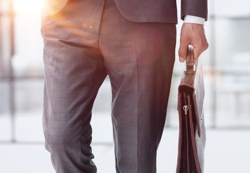 modern businessman with briefcase in modern office, focus on briefcase