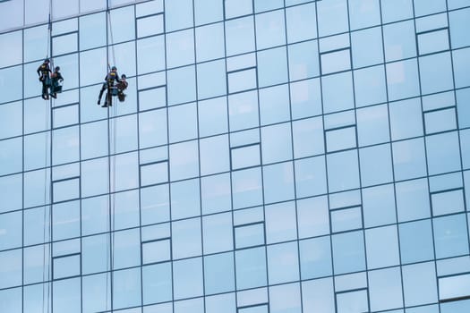 Two Worker Cleaning The Windows Of A High Rise Building Or Skyscraper, With Copy Space