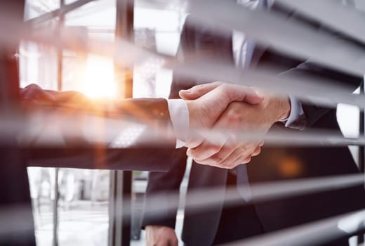 Two business people shaking hands in front of their colleagues