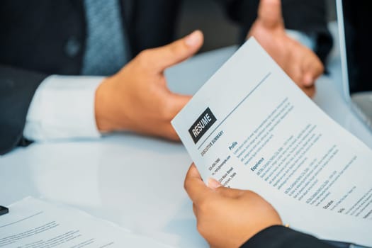 Human resources department manager reads CV resume document of an employee candidate at interview room. Job application, recruit and labor hiring concept. uds