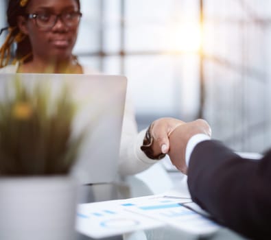 two confident business men shaking hands at the office table