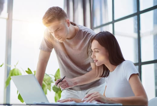 male ceo executive manager mentor giving consultation on financial operations to female colleague intern using laptop sitting in modern office